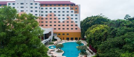 A hotel with a large pool surrounded by lush greenery.