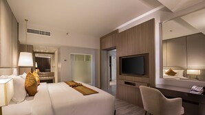 A modern hotel room with a large bed, a desk, a chair, a TV, and a mirror.