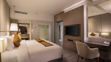 Una habitación de hotel moderna con una cama grande, un escritorio, una silla, un televisor y un espejo.