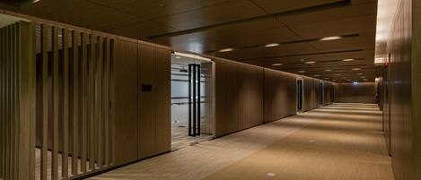 A corridor with wooden paneling and a carpeted floor, leading to a door with a glass panel.