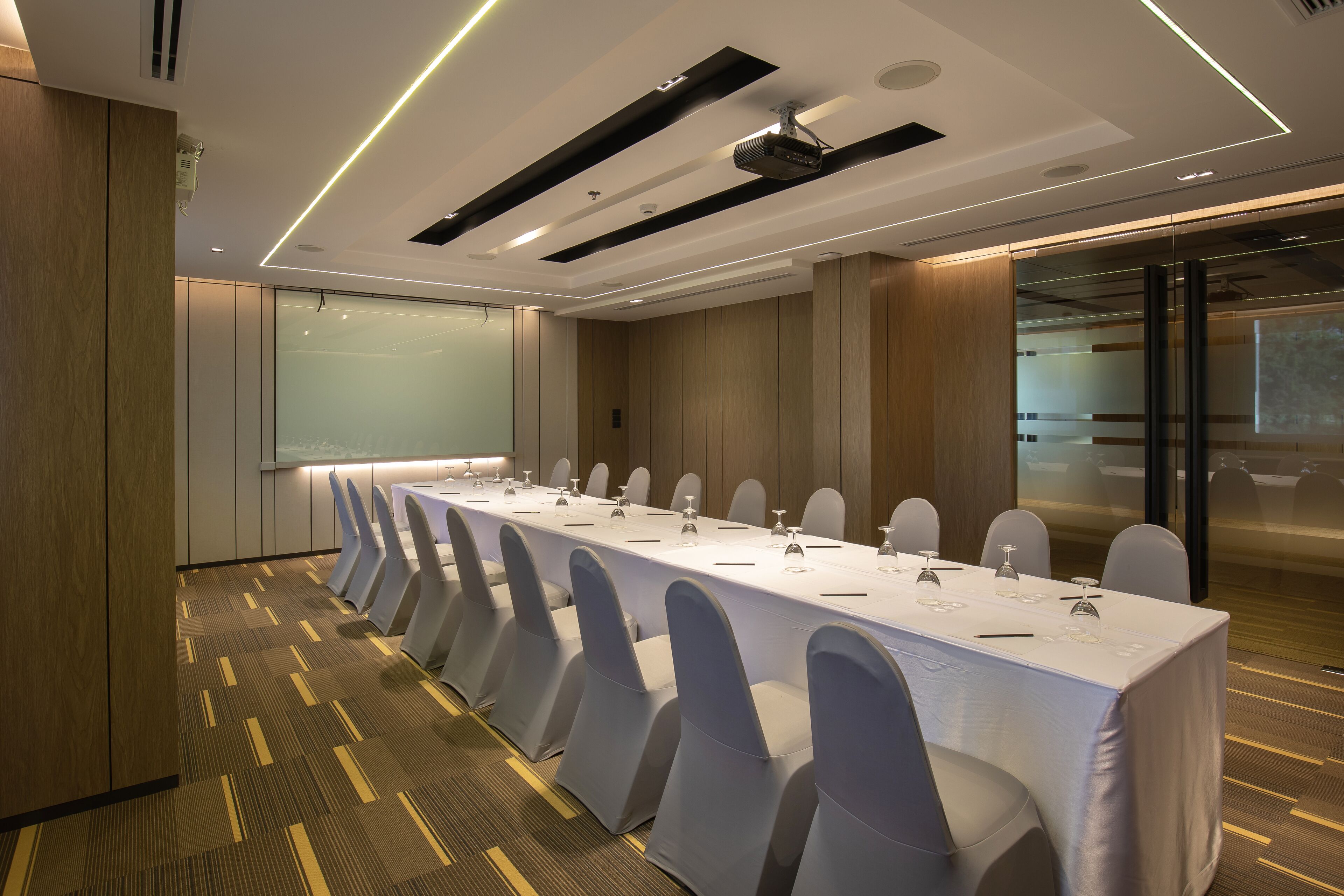 Una sala conferenze con un lungo tavolo, sedie e uno schermo per proiezioni.