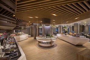 A buffet setup with multiple serving stations, a central decorative column, and a modern ceiling design. - The Heritage Chiang Rai Hotel and Convention (Chiang Rai)