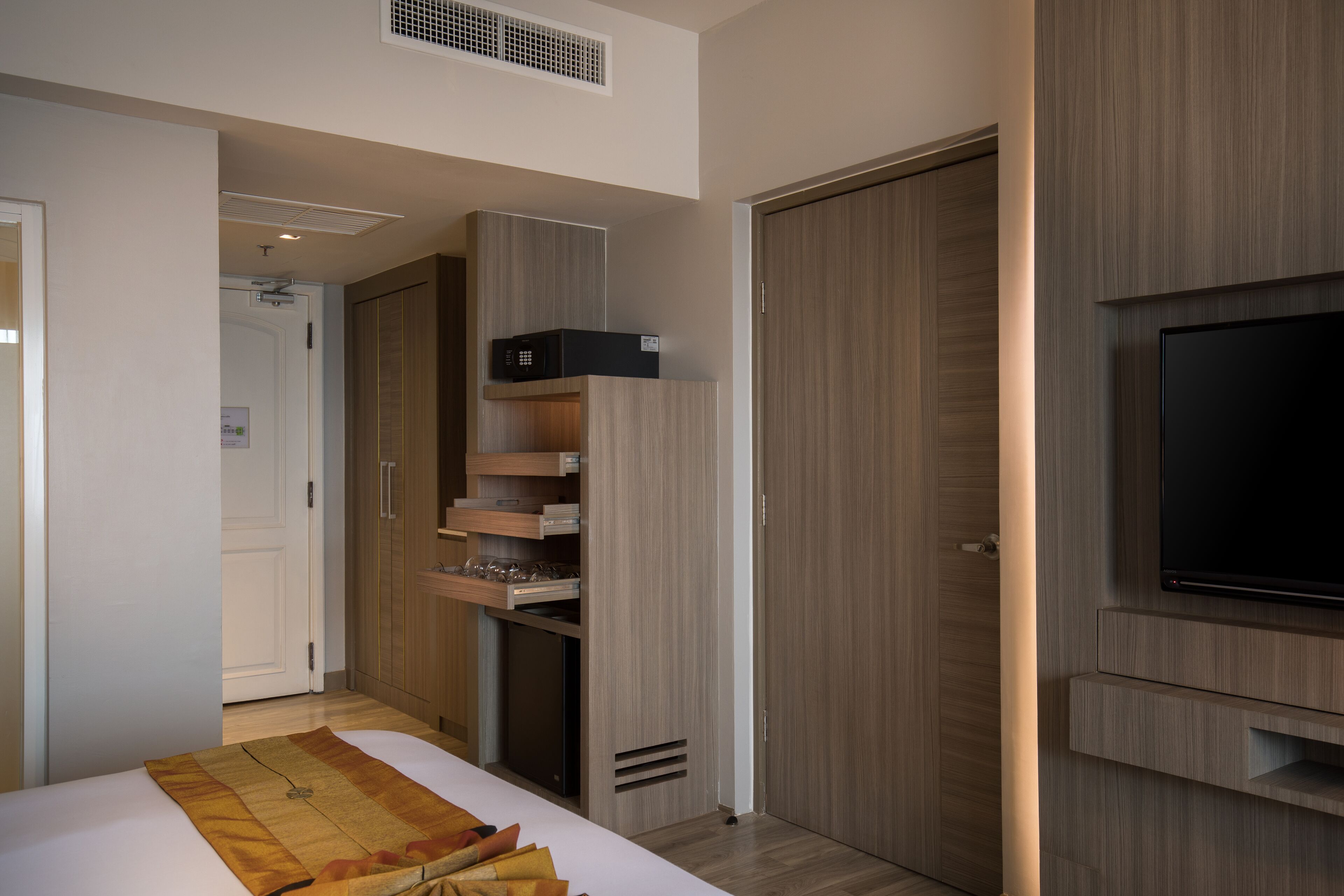 A modern bedroom with a bed, built-in wardrobe, a television, and a microwave.