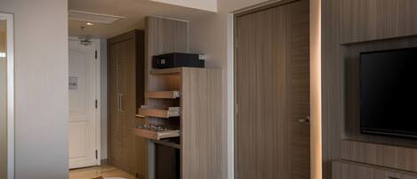A modern bedroom with a bed, built-in wardrobe, a television, and a microwave.