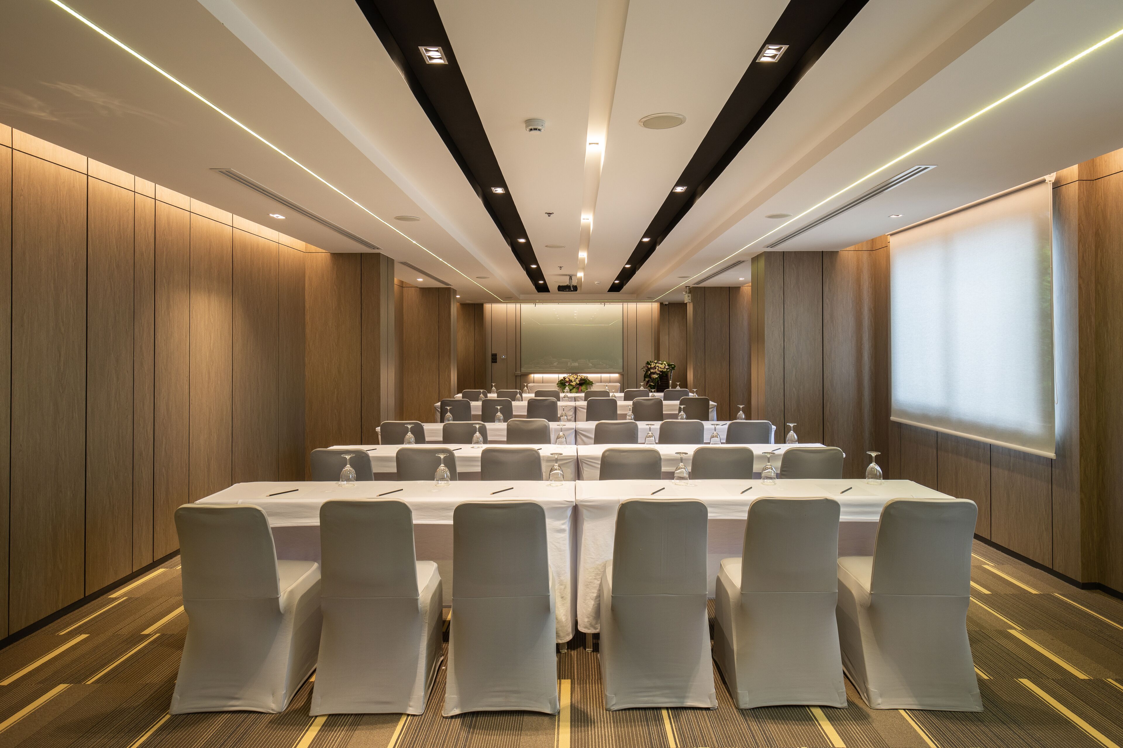 A conference room with a long table, chairs, and a projector screen.