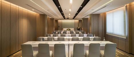 A conference room with a long table, chairs, and a projector screen.