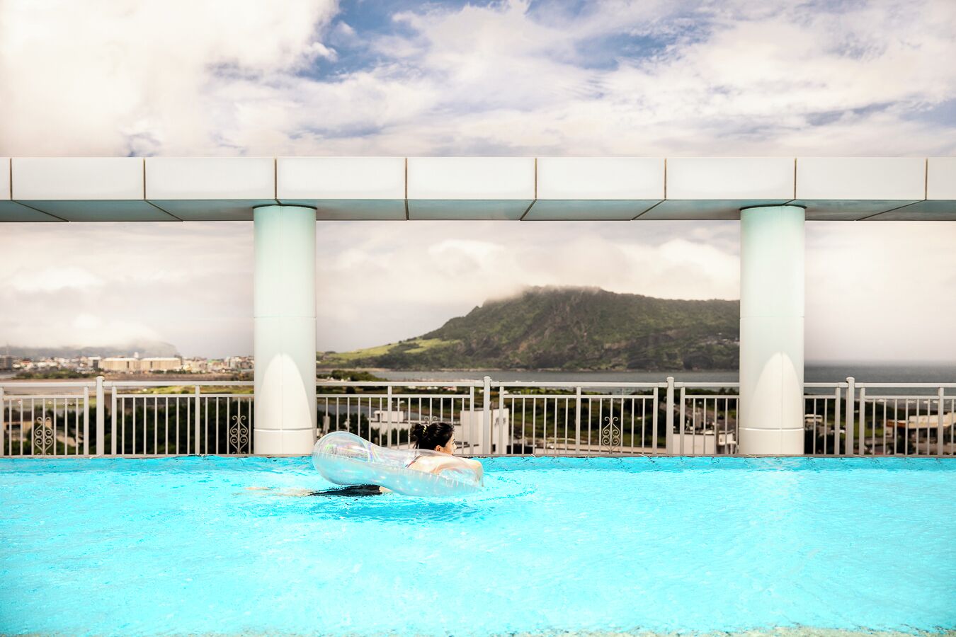 Una piscina con vistas despejadas a un paisaje montañoso y una masa de agua al fondo.