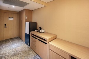 A compact kitchenette with a refrigerator, microwave, and a small countertop with a kettle and cups.