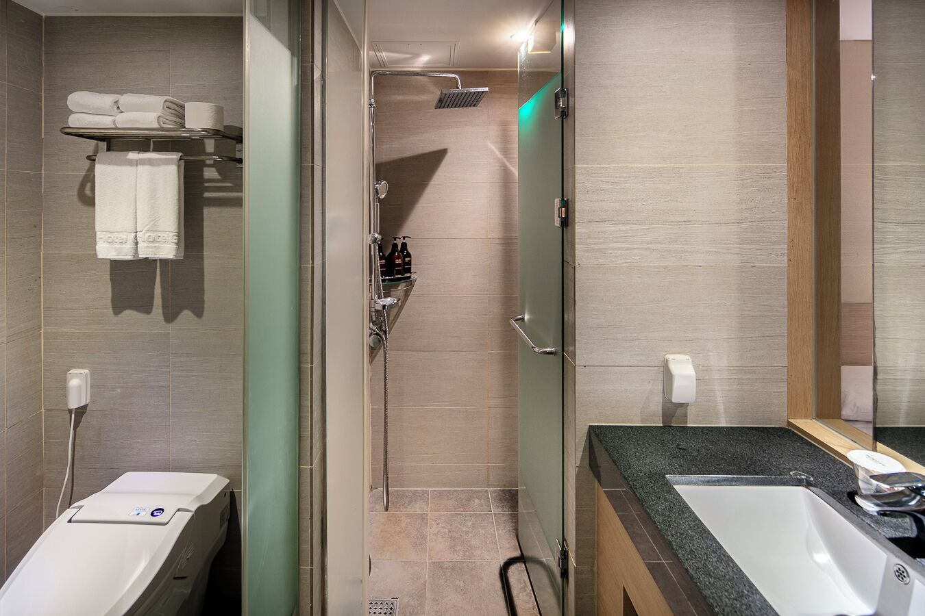 A modern bathroom with a glass-enclosed shower, two sinks, and a vanity with a mirror.