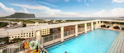 A rooftop pool with a view of a distant mountain and cityscape.