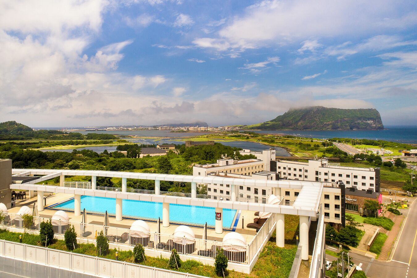 Un hotel con piscina, vista al mar y un paisaje montañoso de fondo.