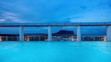 A pool area with a view of a mountain under a bridge.