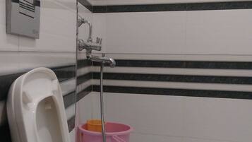 Inodoro blanco con asiento elevado, un cubo rosa y un tirador de la tapa del inodoro fijado a la pared.