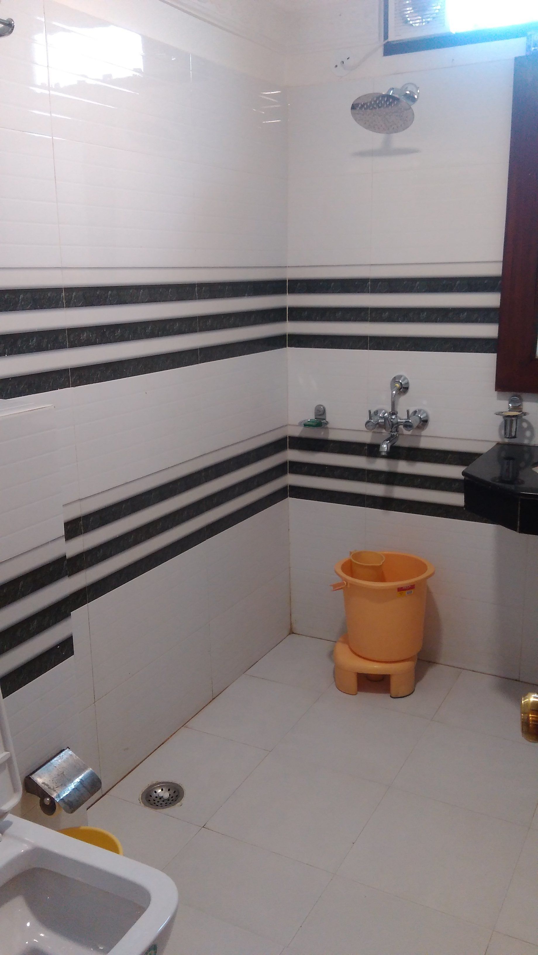 A small bathroom with white and black striped tiles, a toilet, a sink, and a shower.