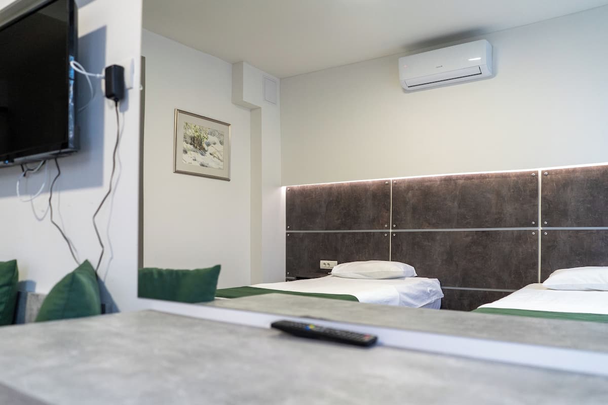 Ein Hotelzimmer mit einem Bett, einem Fernseher und einer Klimaanlage.