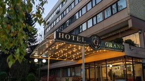A hotel with a covered entrance, multiple floors, and a sign that reads "HOTEL GRAND". - Hotel Grand (Sarajevo)