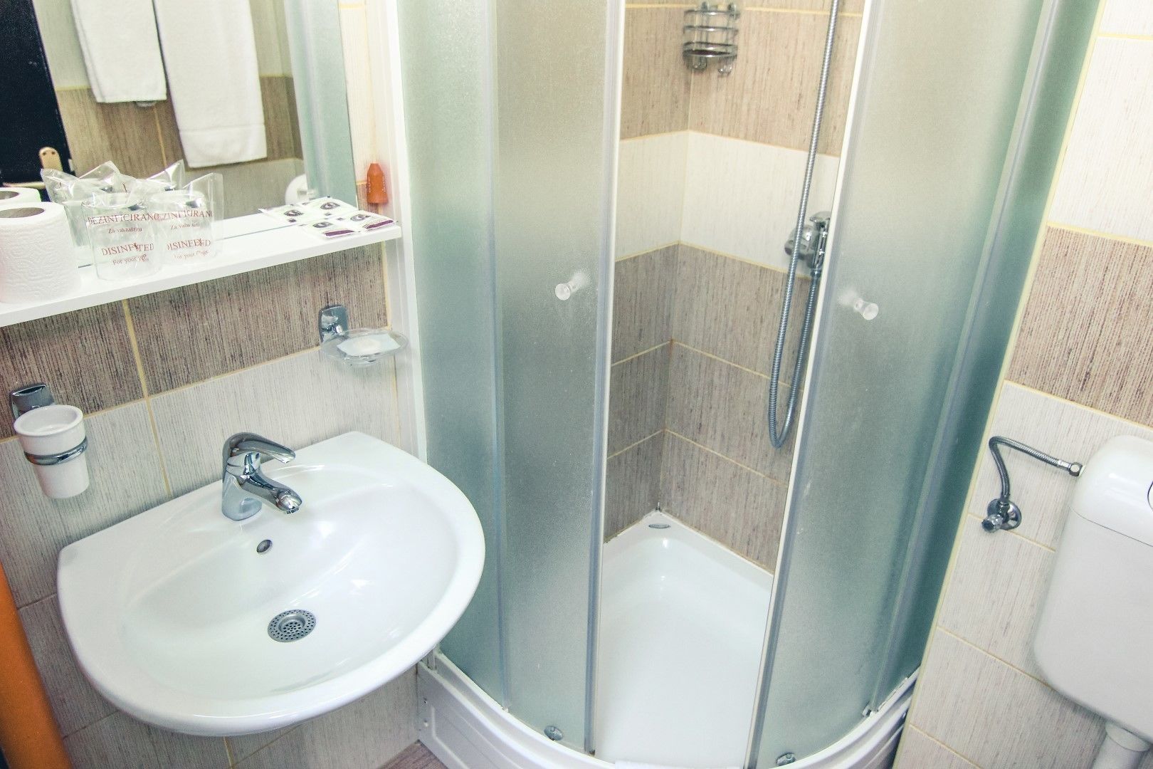 A modern bathroom with a glass-enclosed shower, a white sink, and a mirror above the sink.