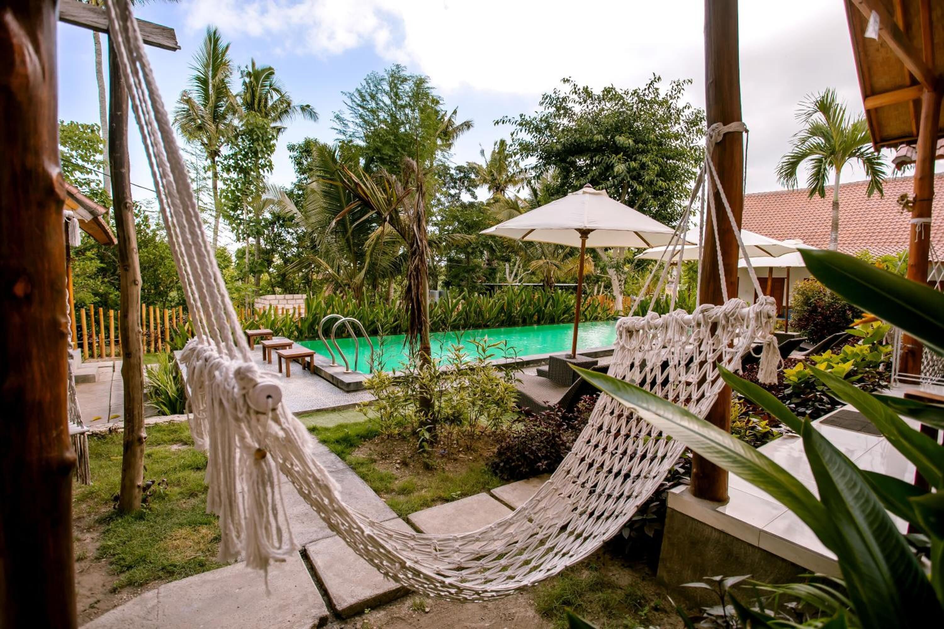 A hammock, a pool, and outdoor seating in a tropical garden setting.
