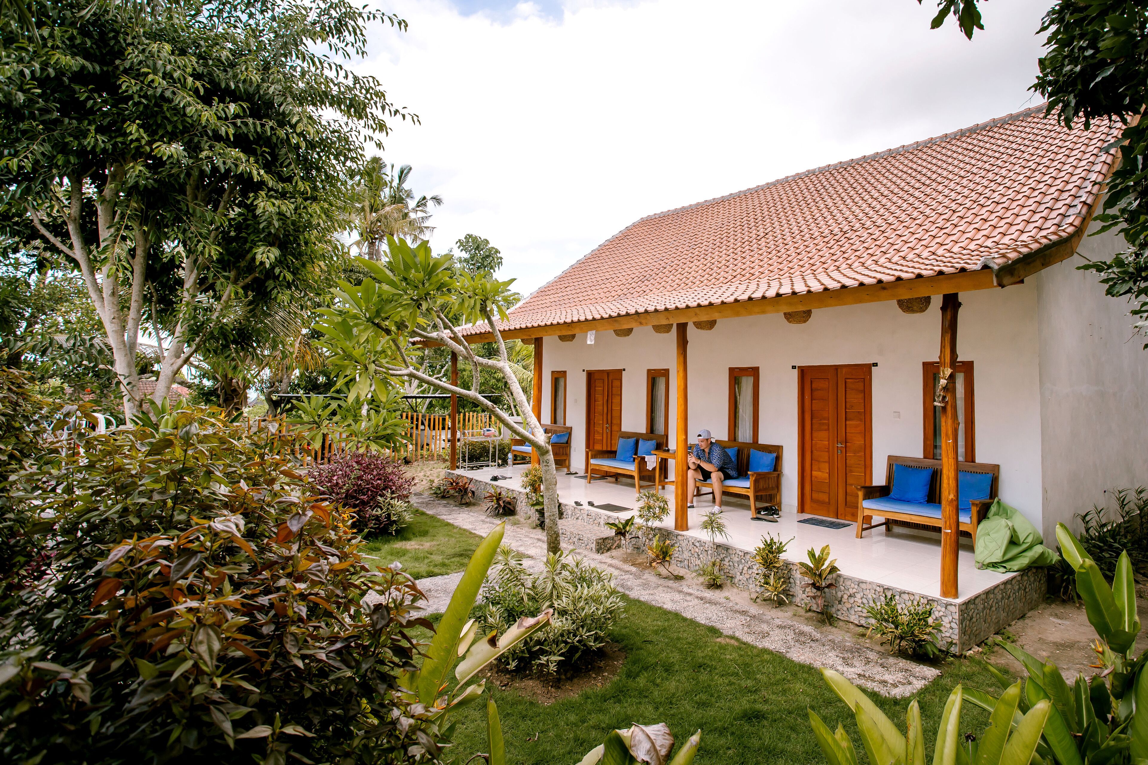 A building with a tiled roof, wooden porch, and seating areas.