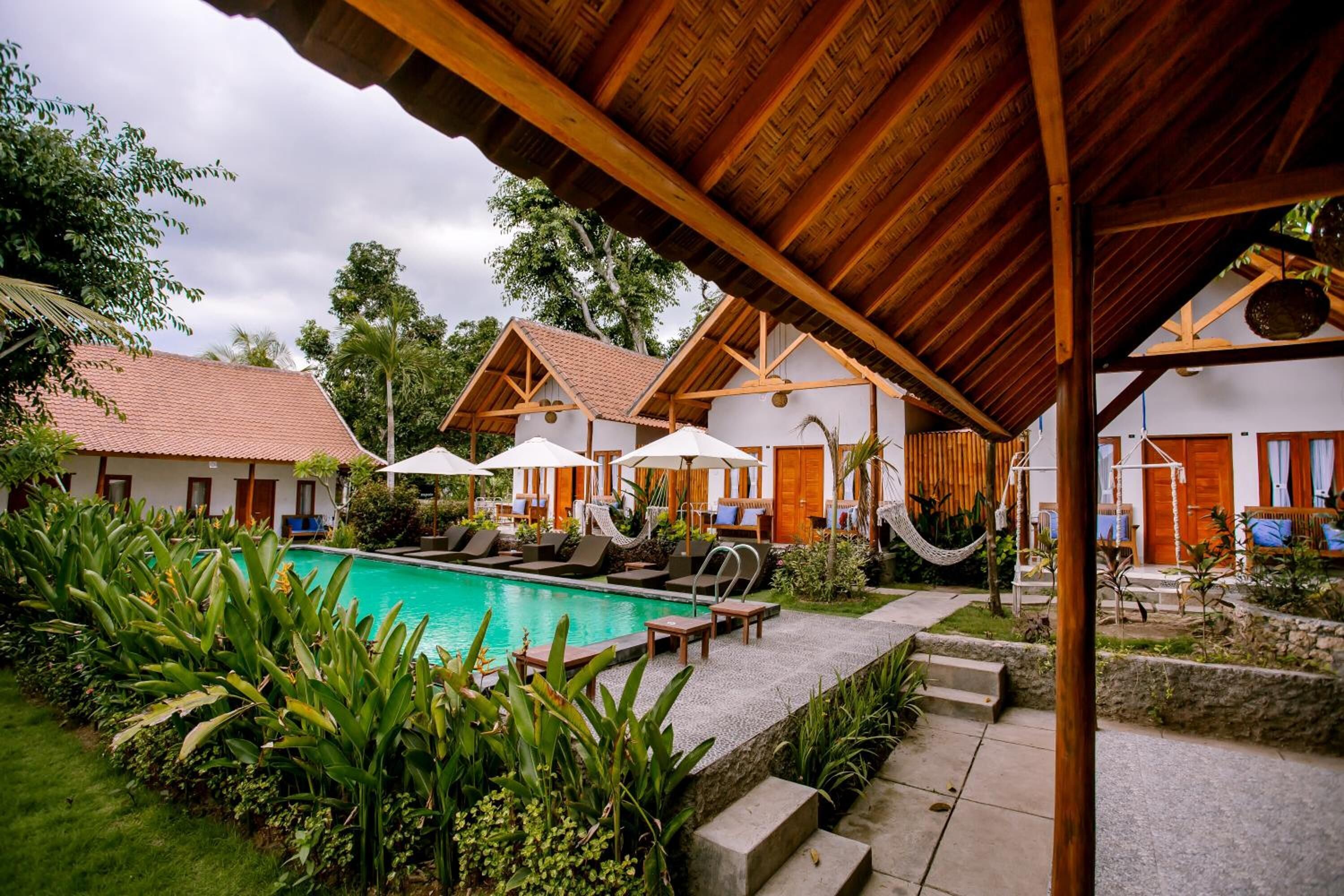A poolside area with lounge chairs, umbrellas, and a wooden pergola.