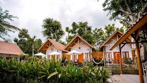 A resort with multiple bungalow-style buildings, outdoor seating areas, and a pool.