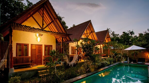 A resort with a swimming pool, wooden villas, and lush greenery.