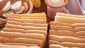 A buffet with various food items including sliced bread, watermelon, bananas, and a candle.