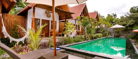 A poolside area with wicker furniture, a hammock, and a covered seating area.