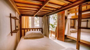 A room with a wooden bunk bed, a single bed, and a small wooden table.