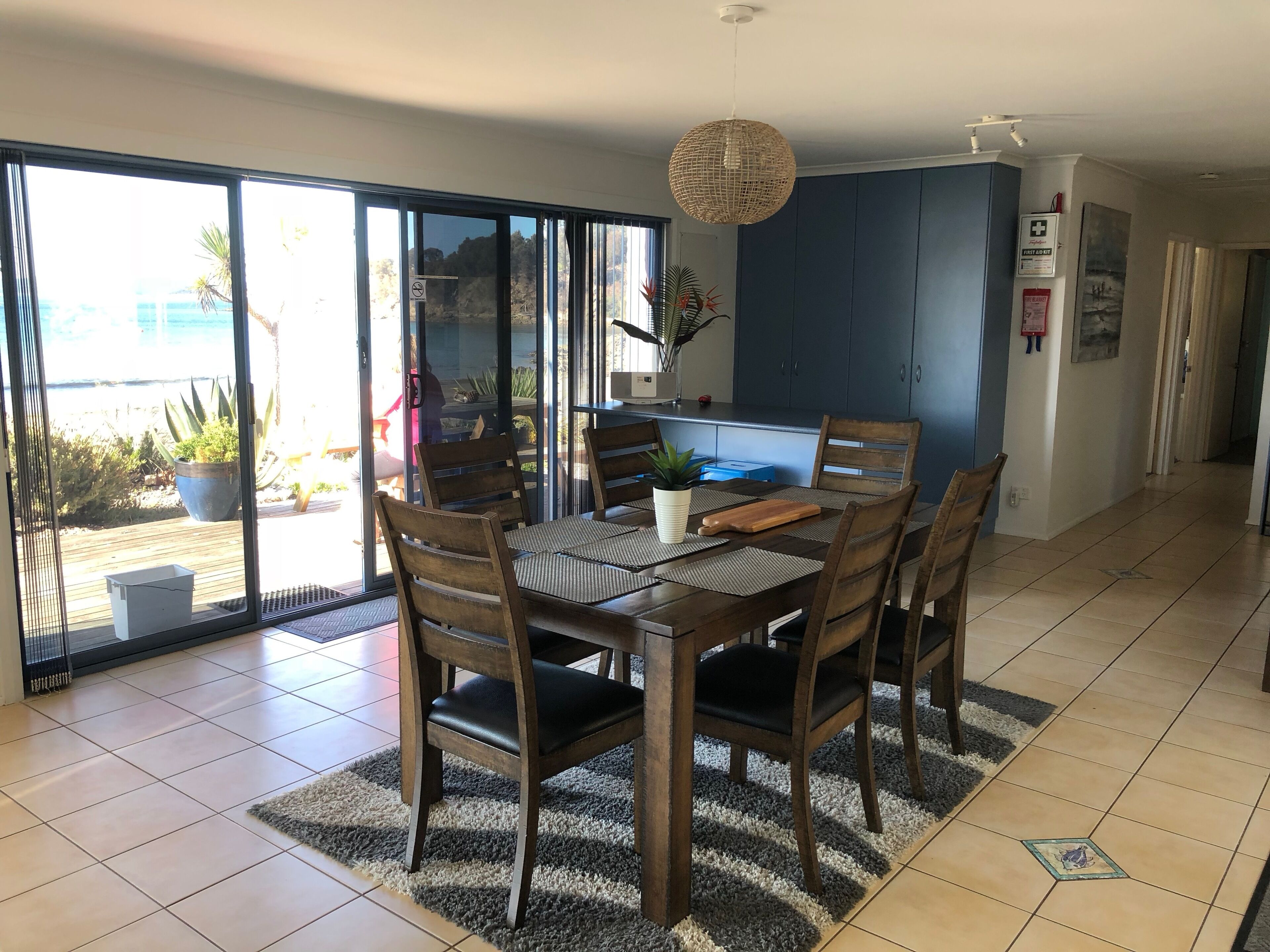 A dining area with a table, chairs, and a hanging light fixture.