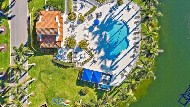 An aerial view of a resort with a swimming pool, lounge areas, and a building with a red roof.