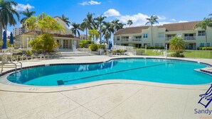 A swimming pool with lounge chairs and palm trees.
