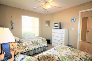 Relax in this serene bedroom with a ceiling fan, TV, and two comfortable beds.