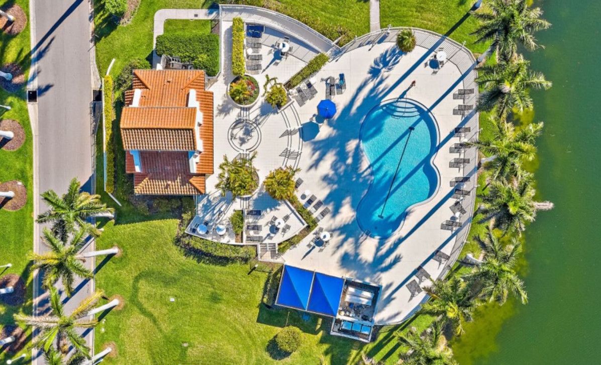 Vue aérienne d’un complexe hôtelier doté d’une piscine, d’espaces de détente et d’un bâtiment au toit rouge.