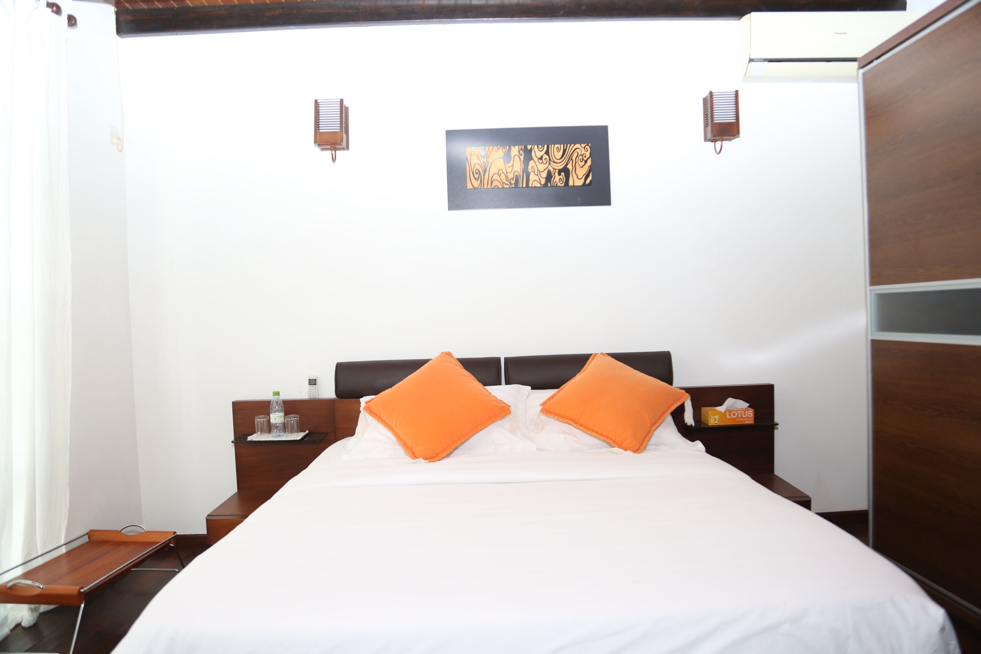 Una habitación de hotel con una cama, dos mesitas de noche, una obra de arte en la pared y un cabecero de madera.