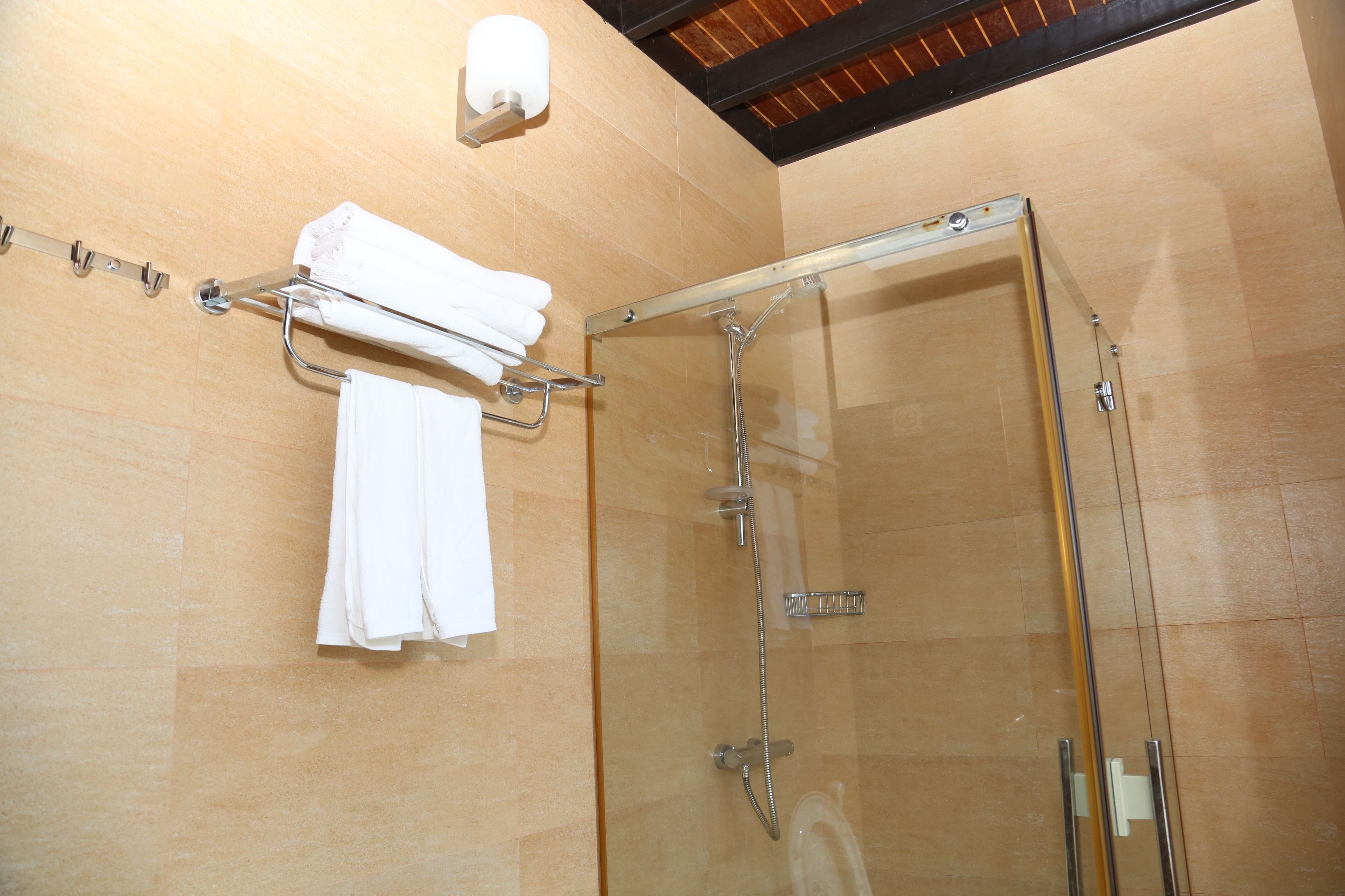 A glass-enclosed shower with a towel rack holding folded towels.