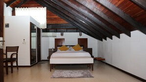 Ein Schlafzimmer mit Holzboden, einem Bett mit weißer Bettwäsche und zwei Kissen, einem Sessel und einem kleinen Tisch.