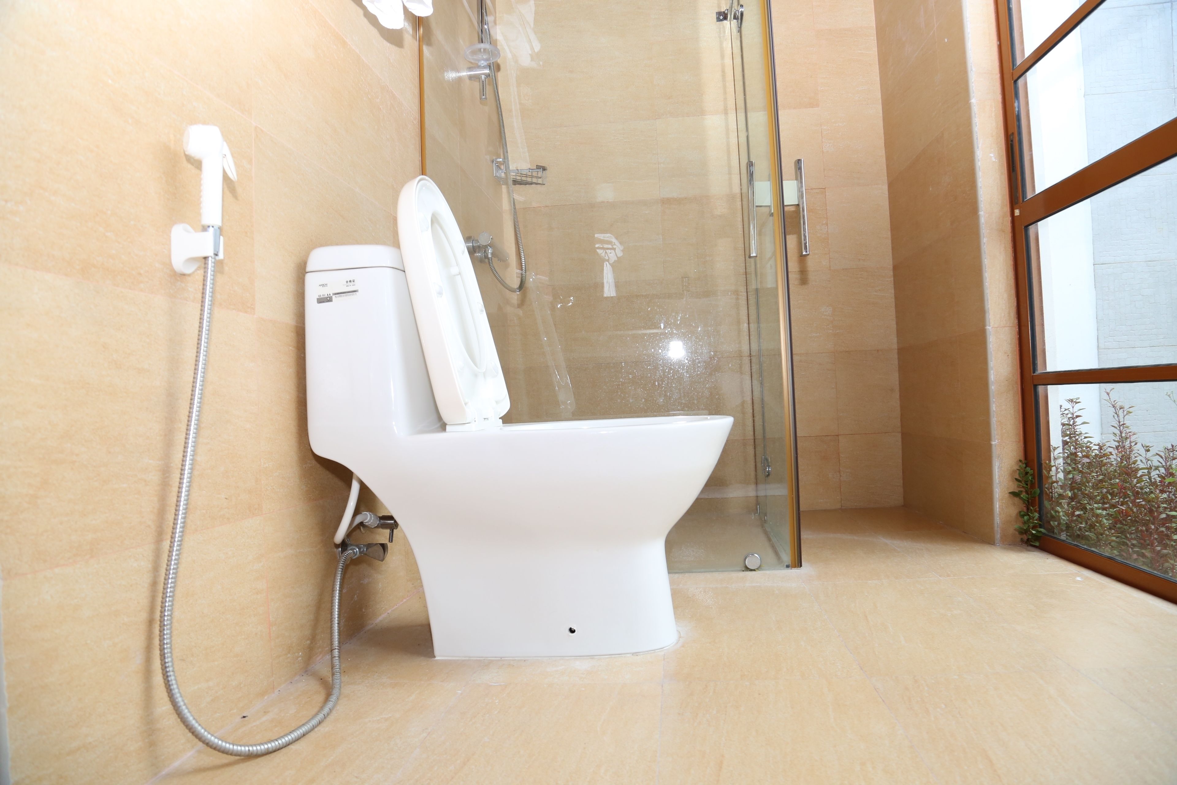 A modern bathroom with a glass-enclosed shower, a white toilet, and a visible water heater.