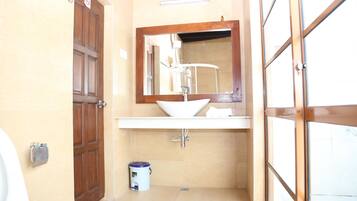 Un baño con puerta de madera, un lavabo blanco y un espejo encima.