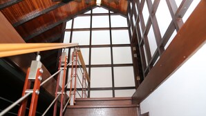 Eine Holztreppe mit Metallgeländern und Blick auf ein großes Fenster mit Gittermuster.