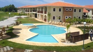 A hotel with a swimming pool, outdoor seating, and a garden area.