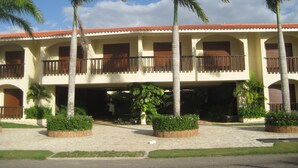 A hotel with a two-story structure, multiple balconies, and palm trees.