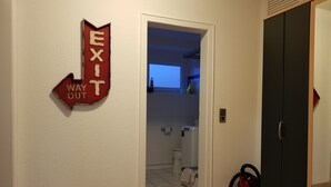 A hallway with a red EXIT sign, a black door, and a visible bathroom with a toilet and a towel rack. - At the gates of Hamburg in the old country (Mittelnkirchen)