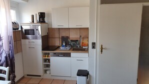 A compact kitchen with white cabinets, a built-in oven, a coffee maker, and a sink. - At the gates of Hamburg in the old country (Mittelnkirchen)