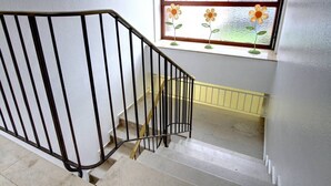 A staircase with a black metal railing, a window with a view of the outside, and a yellow safety handrail. - At the gates of Hamburg in the old country (Mittelnkirchen)