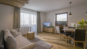 Een moderne woonkamer met een bank, eettafel en televisie.