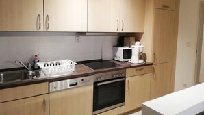 A kitchen with wooden cabinets, a stainless steel sink, a microwave, a coffee maker, and a dishwasher.