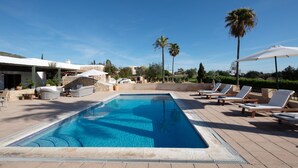 Una piscina con sillas de descanso y una zona de estar cubierta.