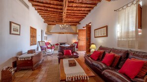 Una sala de estar con techo de madera, sofás de cuero, una mesa de centro de madera y una chimenea.