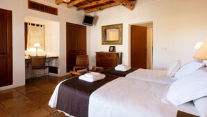 Una habitación con dos camas, un escritorio, una silla, un espejo y un televisor en la pared.